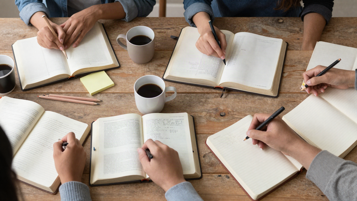 Open Bibles, notebooks and coffee on a wooden table during a small-group Bible study